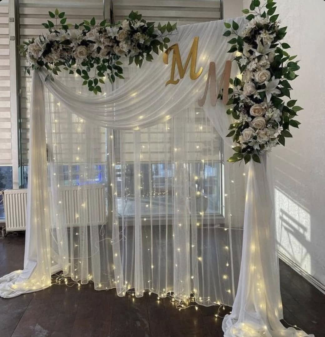 Wedding backdrop — white drapes with fairy lights and flowers